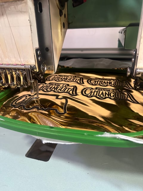 Laser engraving machine cutting fabric with Chang branding design in gold and black