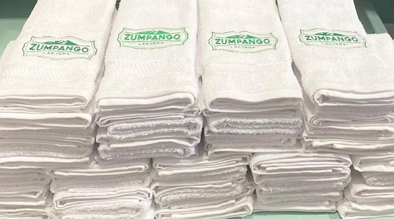 Stacked white cloth napkins with Zumpango green branding arranged in rows