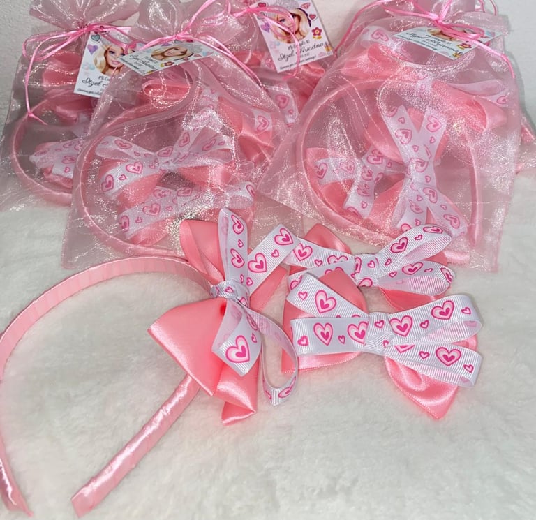 Collection of pink headbands and hair accessories with hearts pattern and mesh bows displayed in packages