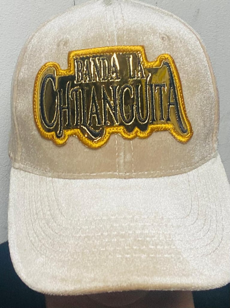 Beige and white baseball cap with gold-trimmed embroidered patch reading Banda La Chancla