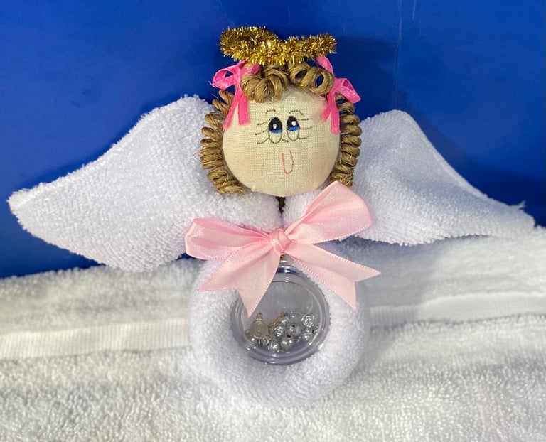 Decorative handmade angel ornament with painted face, golden glitter crown, pink ribbons, white fabric wings, and clear globe base on blue background
