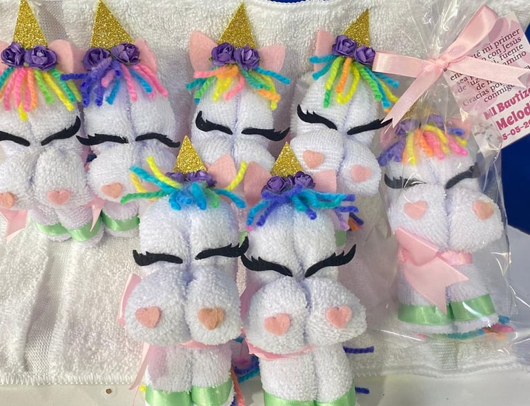 Plush unicorn toys with white bodies, rainbow manes, gold horns, and closed eyes arranged in a group display