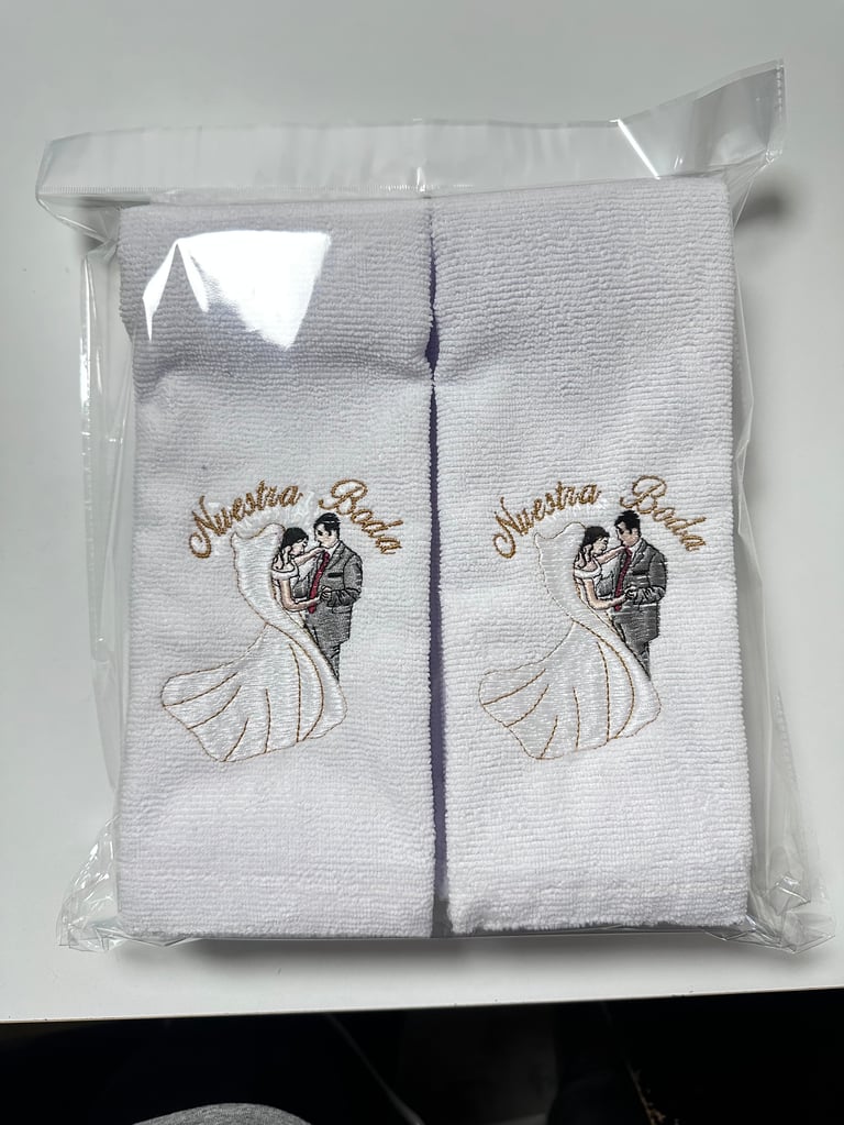 Package of two white towels with Nuestra Boda bride and groom embroidery design