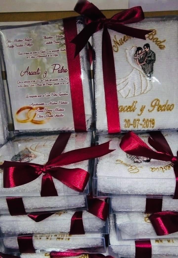 Stack of wedding invitation cards with gold accents and burgundy ribbons bows