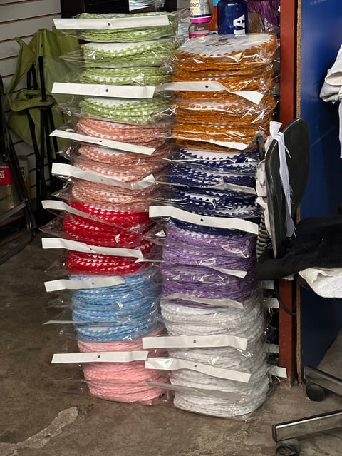 Stacks of colorful folded fabrics and textiles organized on a wooden table in a storage or workspace area