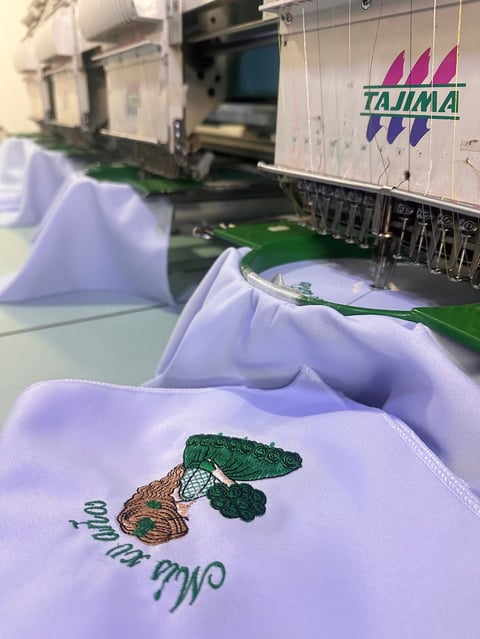 Embroidered fabric showing a turtle design on white material at an industrial embroidery machine with Tajima branding