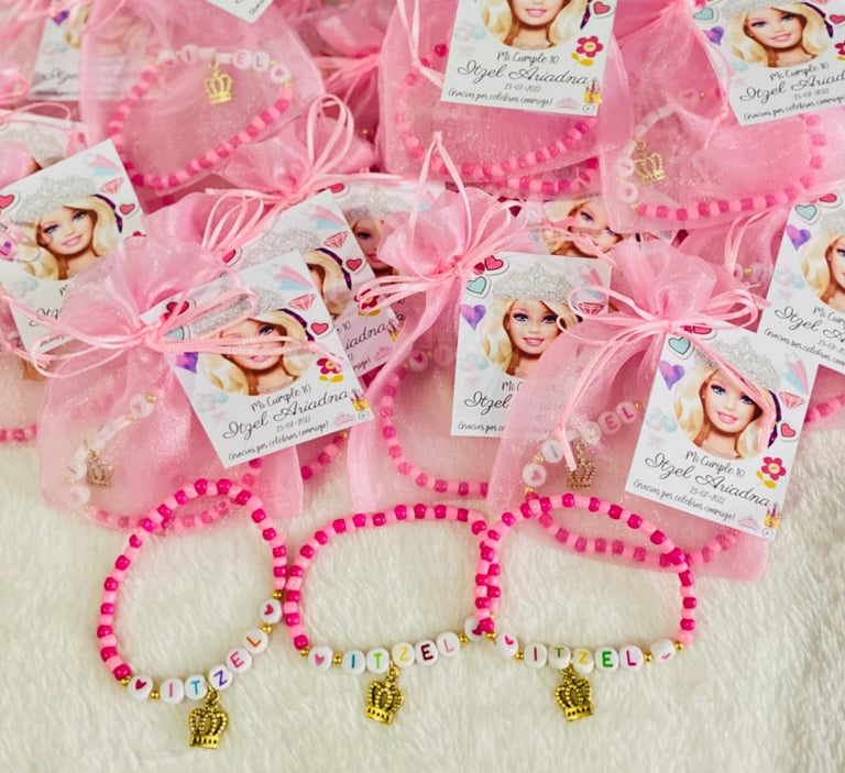 Pink beaded bracelets with gold charms and personalized gift bags with photo labels for a childrens party favor