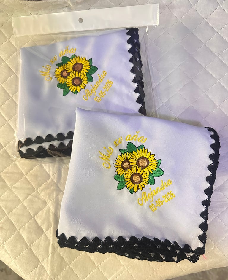 Two packaged white handkerchiefs with sunflower design and black scalloped edges on cream quilted background