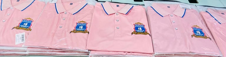 Cuatro camisas rosadas con botones y logotipos azules bordados en fila sobre perchas