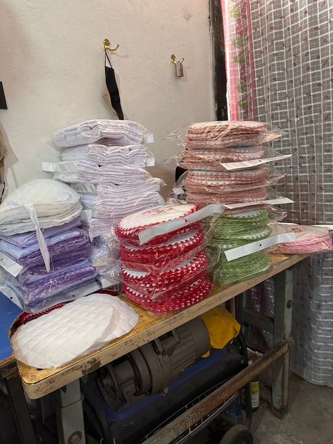 Stacked rolls of colorful patterned fabric or ribbon stored on shelves in a workshop or storage area